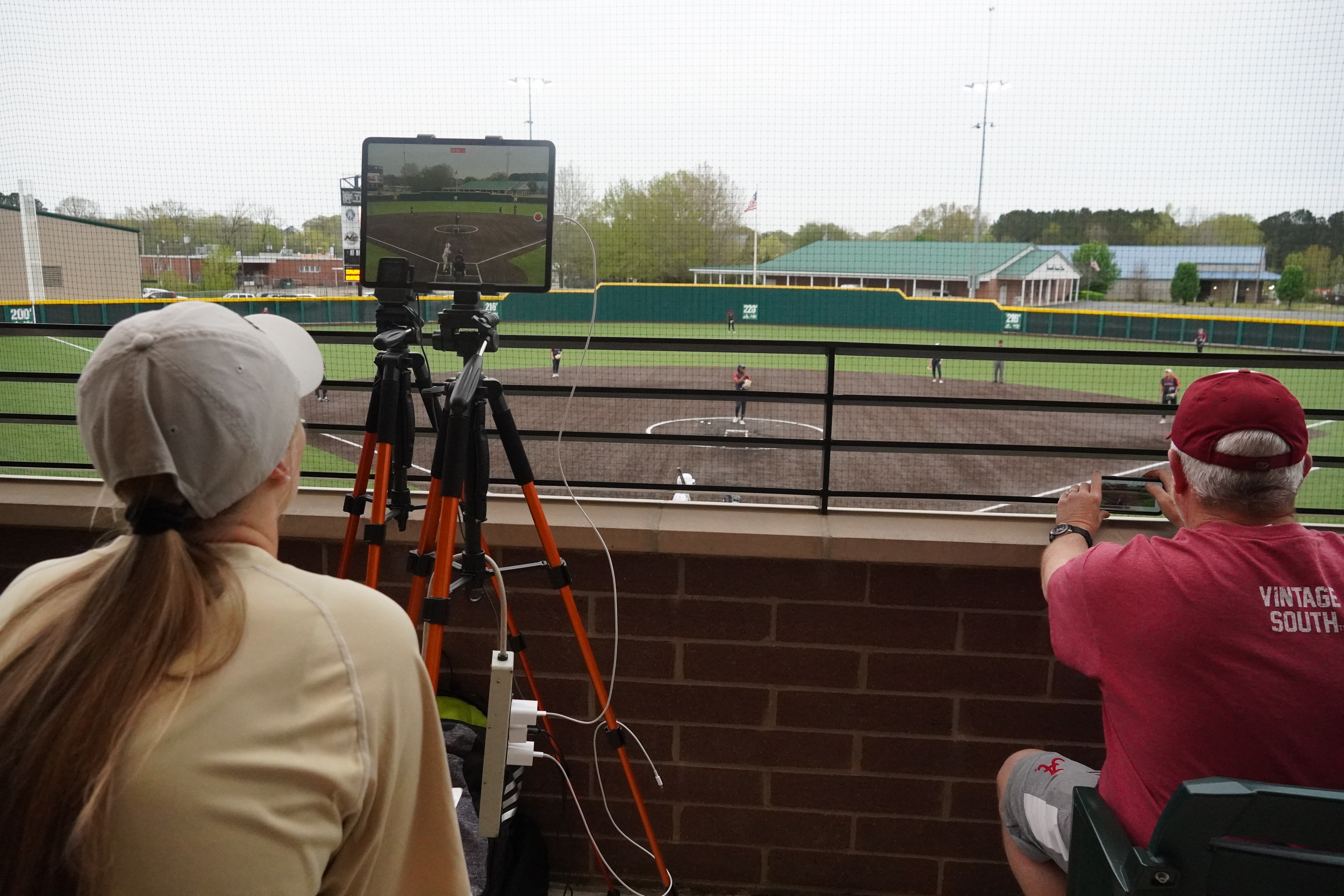 student taking a video of the softball game