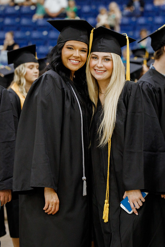Candid graduation photo of two smiling graduates