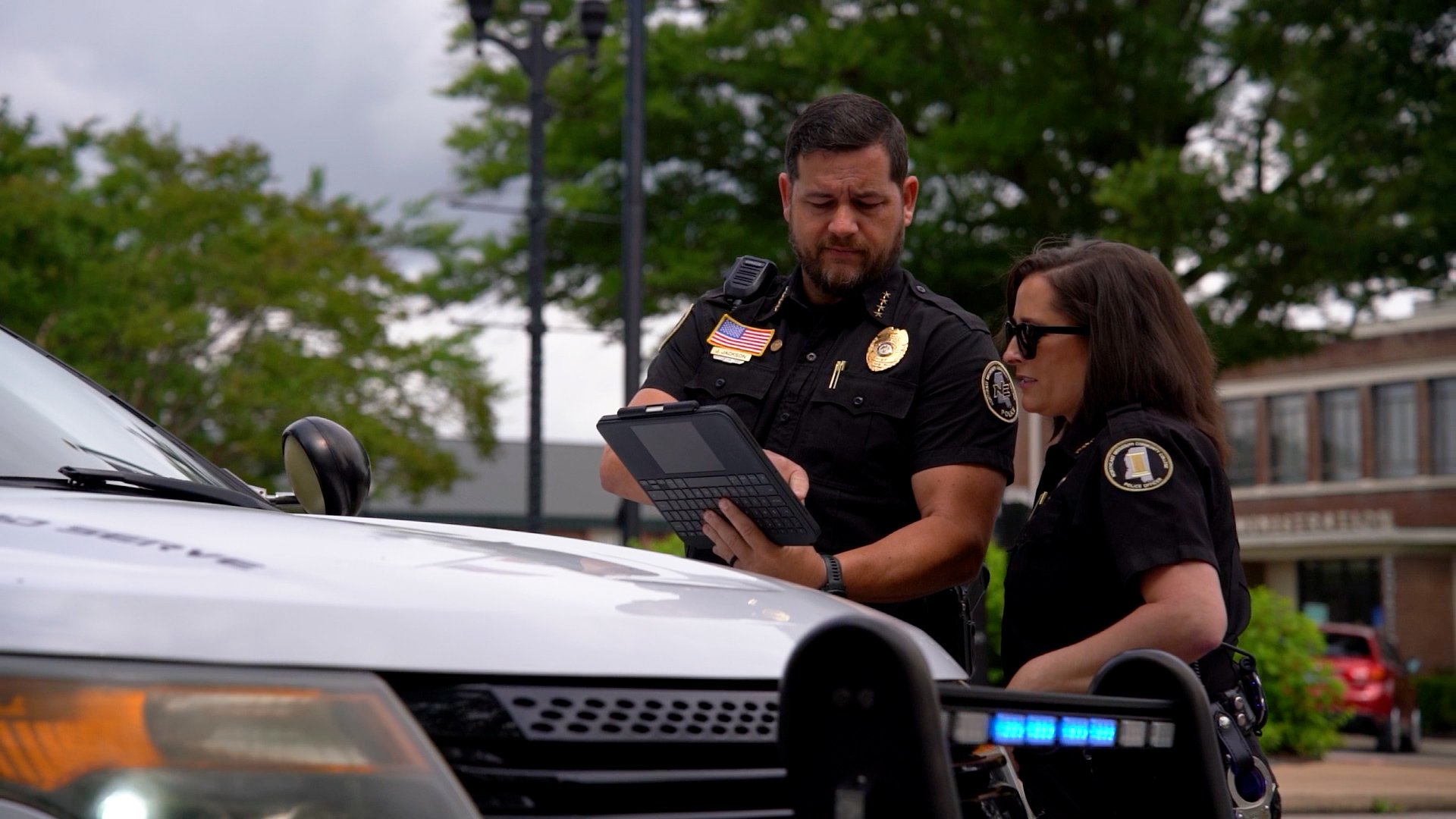 two police officers beside a police car looking at iPad