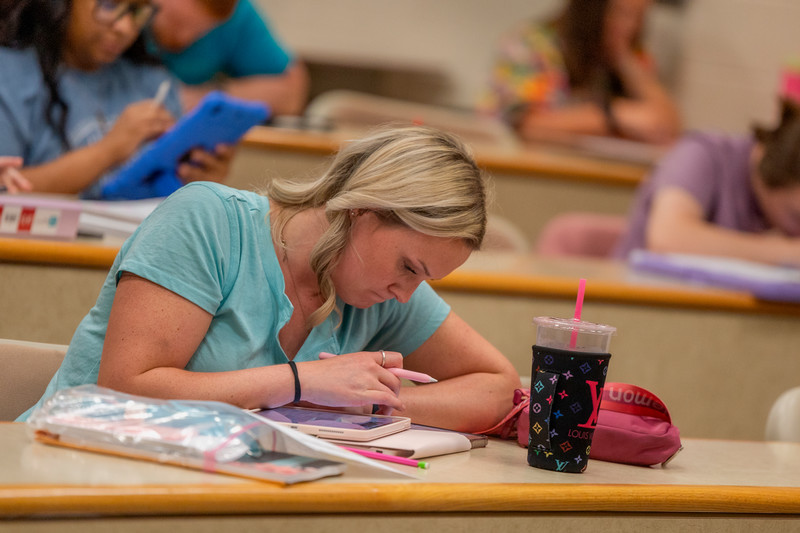 Female student looking down at her iPad taking notes.