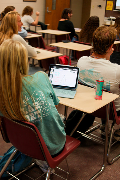 student sitting in classroom at desk with iPad