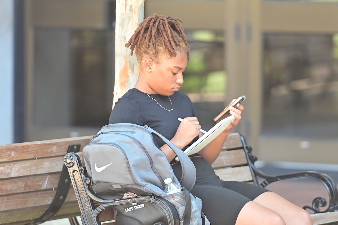 student sitting on bench with iPad